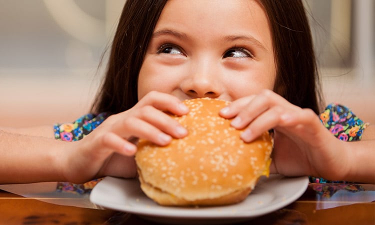A girl enjoys a hamburger at one of the on-site dining options